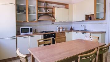 A compact kitchen with a microwave, stove, cabinets, and a dining table with chairs.