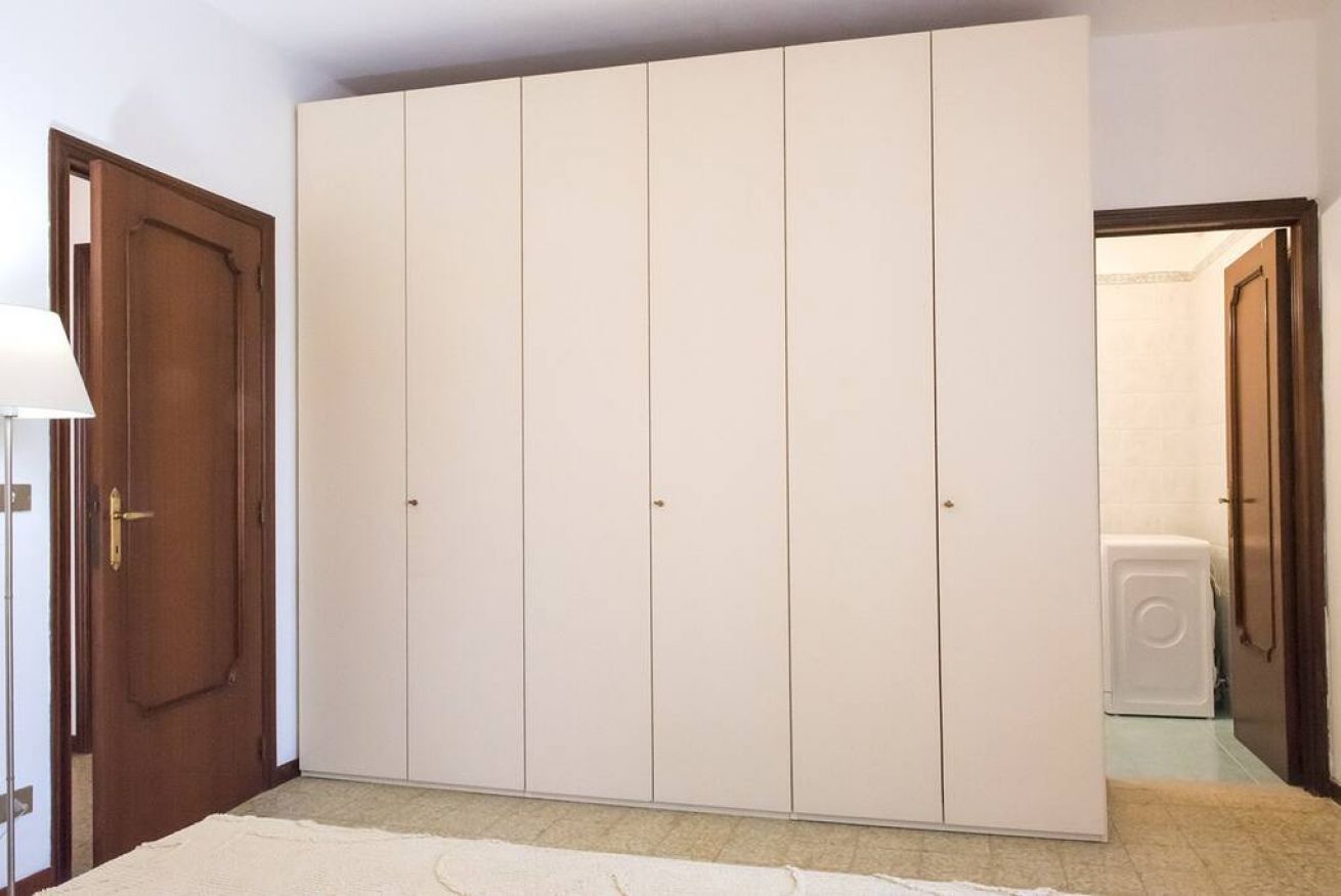 A room with a large wardrobe, a door, and a washing machine.