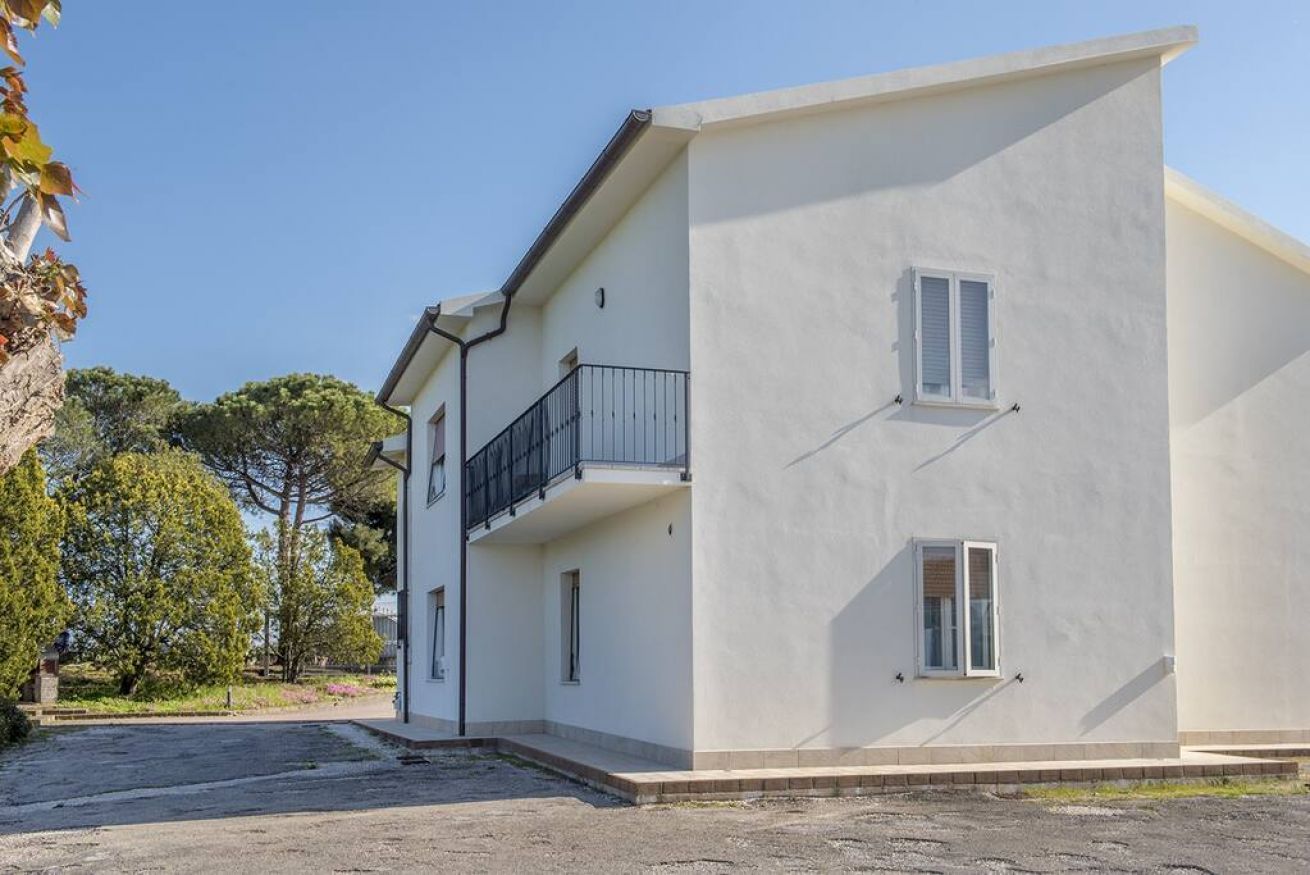A two-story building with a balcony, a small window, and a door.