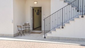 A building entrance with a staircase, a door, and a small table with chairs outside.