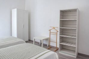 A bedroom with two beds, a wardrobe, a small table, and a hanging shelf. - A11 - Varano, delightful three-room apartment with garden (Ancona)