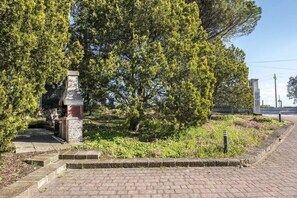 Un sendero pavimentado que conduce a un monumento de piedra rodeado de follaje.