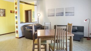 A dining area with a table and chairs, a sofa, and a lamp.