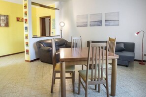 Uma área de refeições com mesa, cadeiras, um sofá e um abajur.
