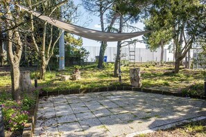 A garden with a hammock, stone benches, and a paved area surrounded by trees. - A11 - Varano, delightful three-room apartment with garden (Ancona)