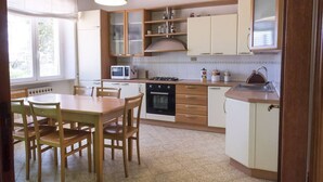 A kitchen with a dining table, chairs, cabinets, a microwave, stove, and a sink.