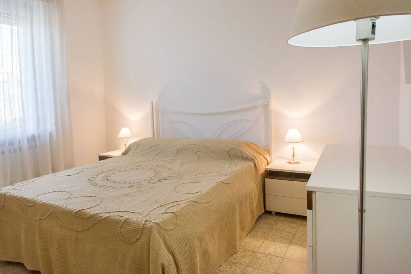 A bedroom with a bed, bedside lamps, a nightstand, and a cabinet.