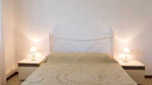 A bedroom with a bed, two bedside lamps, and a nightstand.