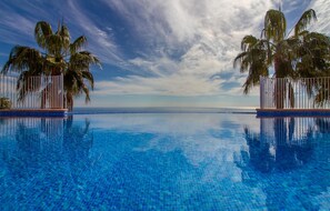 A clear blue pool with a view of the ocean and palm trees on either side. - Beach front apartment (El Poble Nou de Benita)