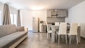 A modern kitchen with a dining area, a sofa, and a window with curtains. - "The LOFT - ITALY COURSE" (Pisa)