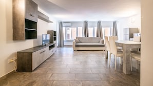 A modern living room with a sofa, TV, and dining area. - "The LOFT - ITALY COURSE" (Pisa)
