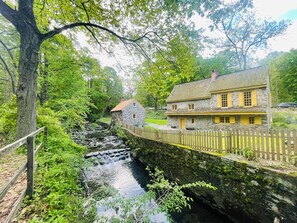 Une maison en pierre avec une clôture en bois et un petit ruisseau.