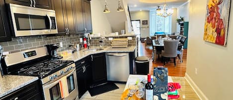 A modern kitchen with dark cabinets, stainless steel appliances, and a dining area with a wooden table and chairs.