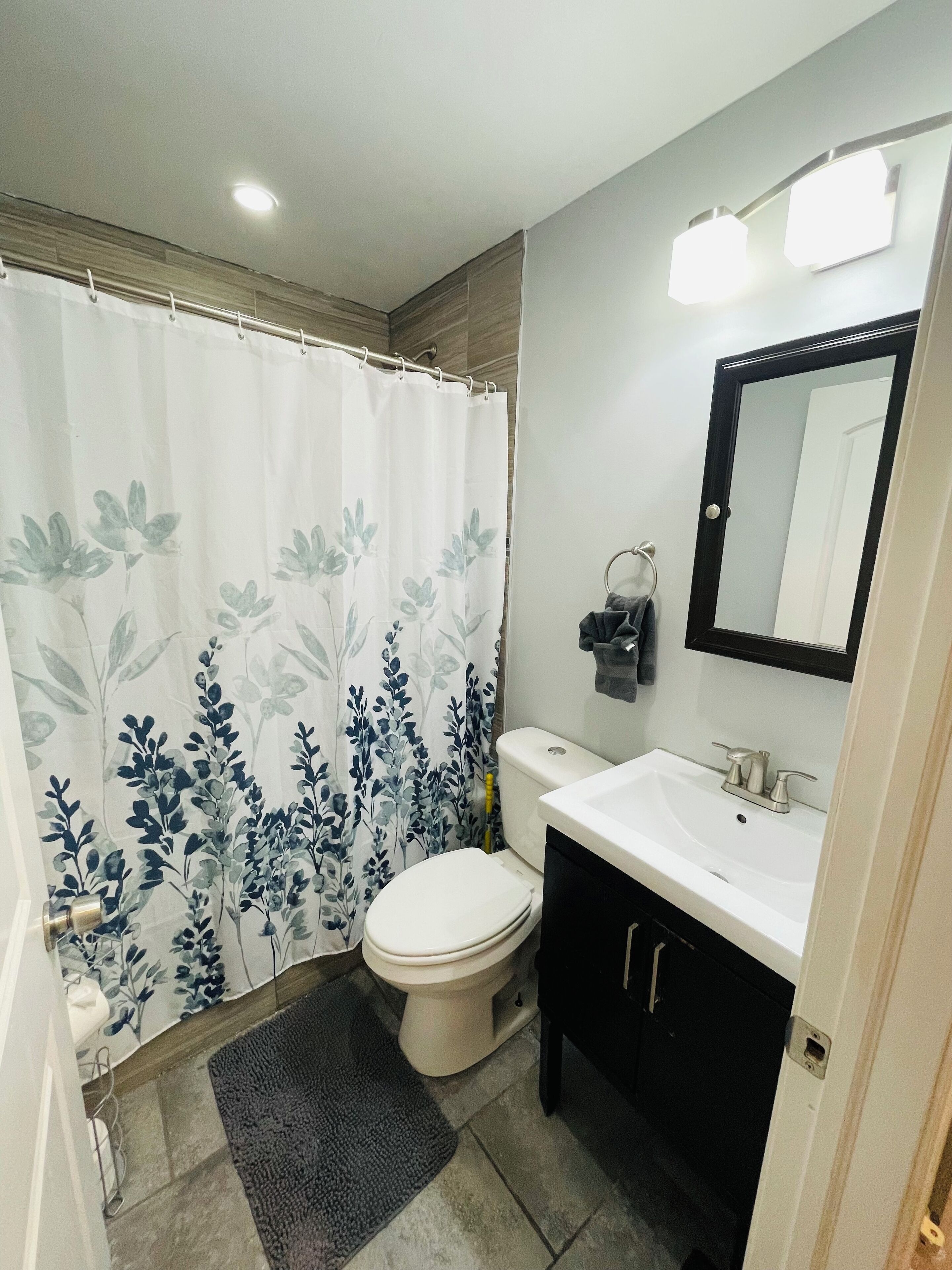 A bathroom with a toilet, sink, and shower curtain.