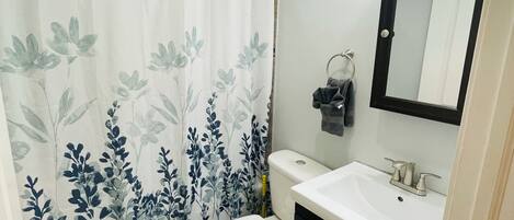 A bathroom with a toilet, sink, and shower curtain.