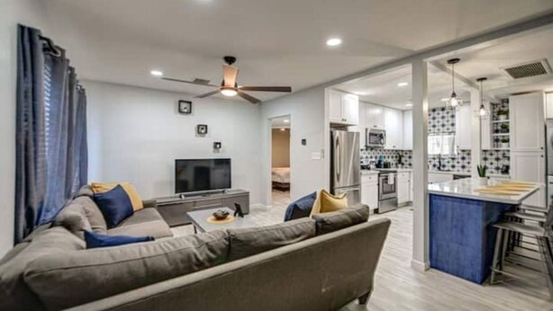 A modern living room with a sofa, TV, and a kitchen area with a bar. - Modern-Downtown-PHXairport-Firepit-BBQ-MiniGolf (Phoenix)