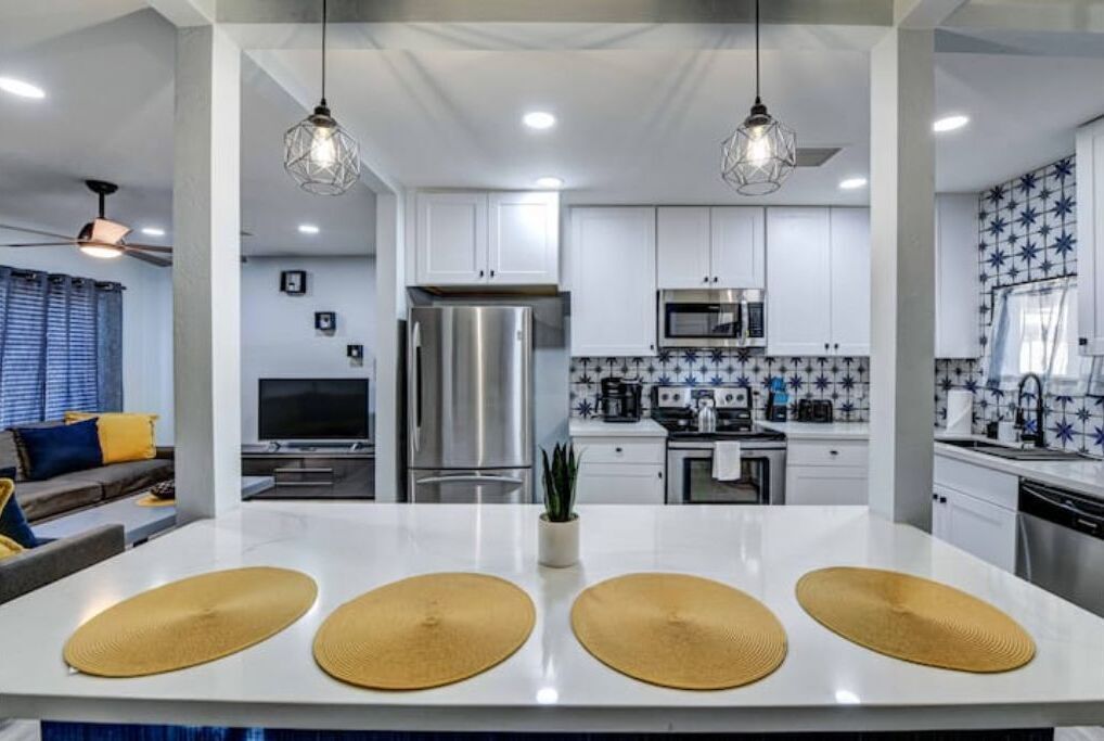 A modern kitchen with white cabinets, stainless steel appliances, and a central island with three woven placemats.