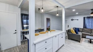 A modern kitchen with white cabinets, a central island with a white countertop, and pendant lighting. - Modern-Downtown-PHXairport-Firepit-BBQ-MiniGolf (Phoenix)