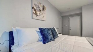 A bedroom with a bed, white walls, a door, and a painting. - Modern-Downtown-PHXairport-Firepit-BBQ-MiniGolf (Phoenix)