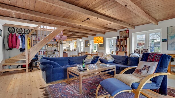 Ein gemütliches Wohnzimmer mit Holzboden, einer Sofagarnitur, einem Couchtisch und einem Bücherregal.