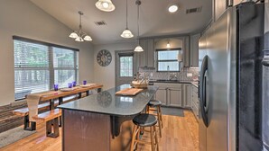 A modern kitchen with a central island, pendant lighting, and a stainless steel refrigerator. - Hogden Home Near the Black Fork River & Trails! (Hodgen)