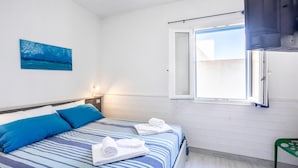 Ein Schlafzimmer mit einem Bett, einem Gemälde, einem Fenster und einem grünen Sessel.