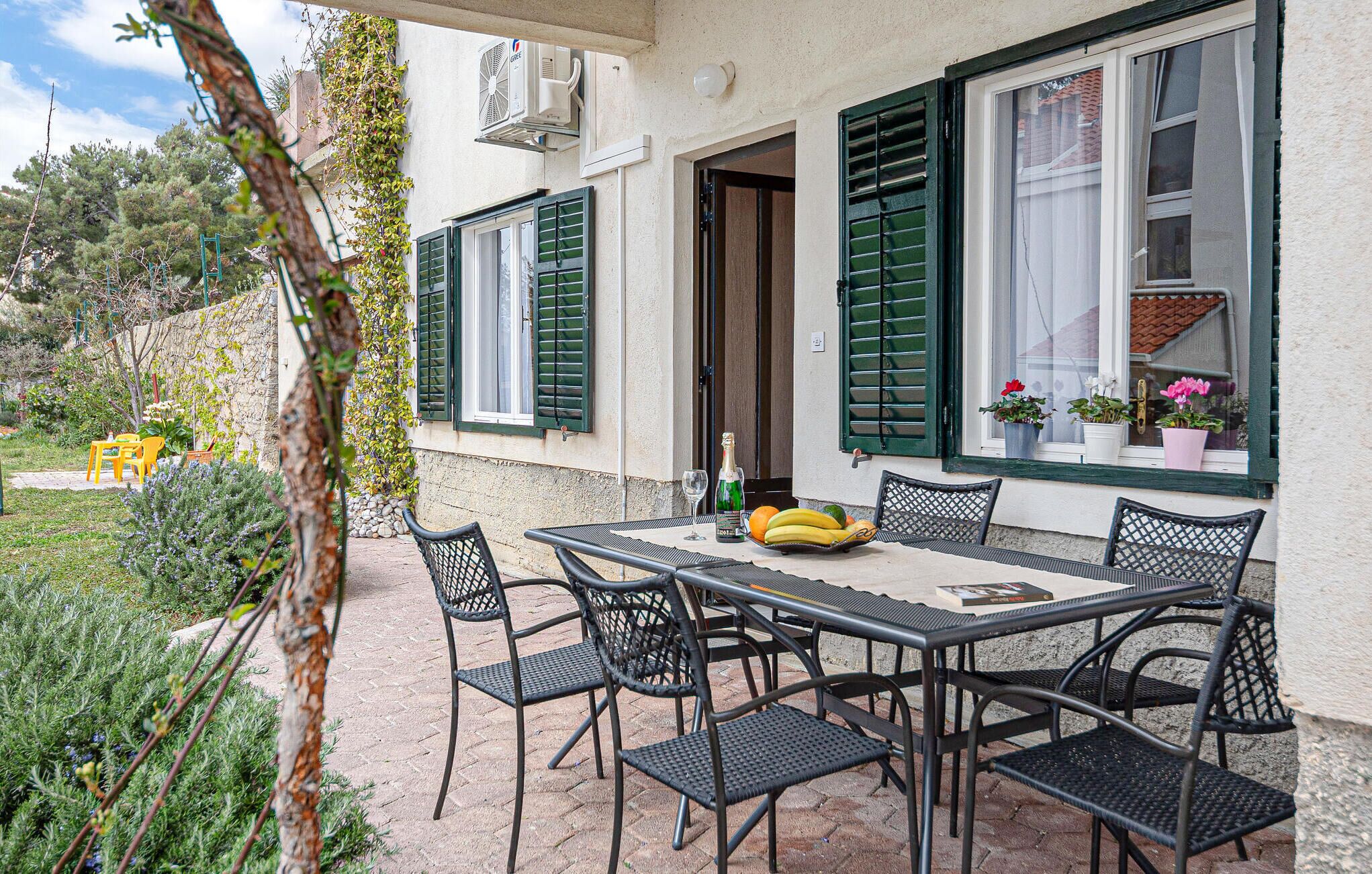 An outdoor patio with a table and chairs, a bottle of champagne, and a bowl of fruit.
