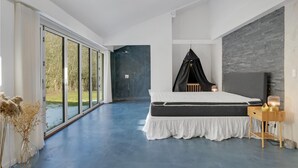 A modern bedroom with a large bed, a black canopy, a wooden bedside table, and a view of the outdoors through large windows. - Stunning home in Gilleleje with kitchen (Gilleleje)