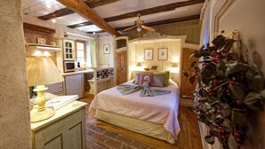 Una camera accogliente con un letto, un comodino, una lampada e un angolo cottura.