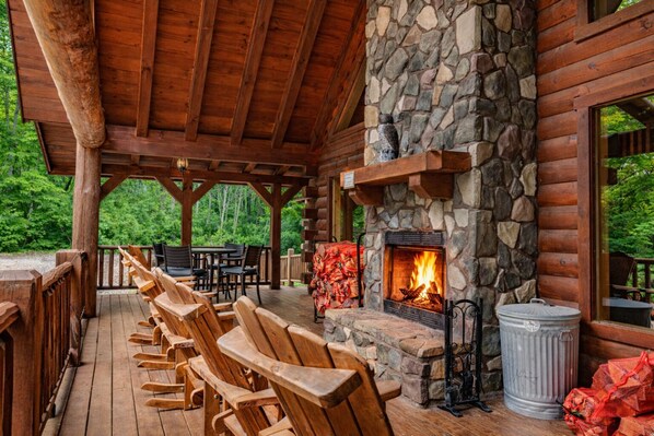 Una terraza de madera con mobiliario exterior y una chimenea de piedra.