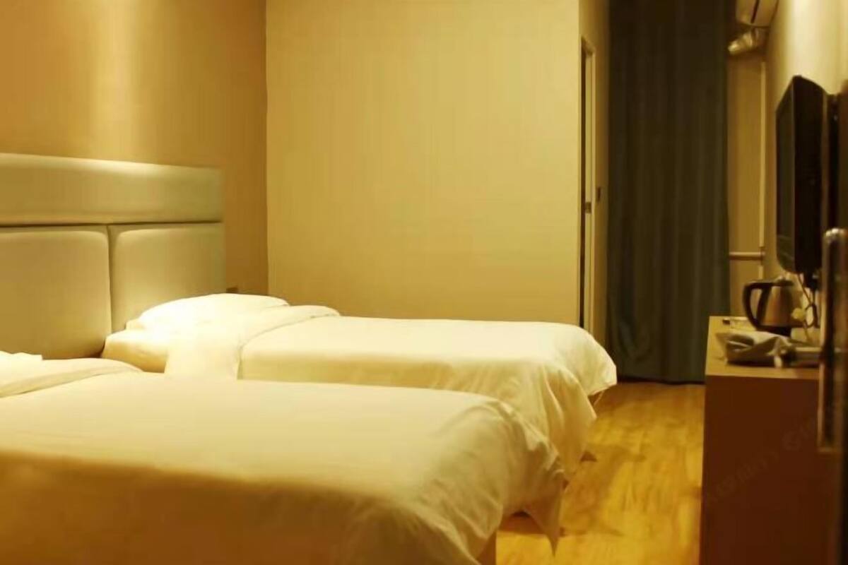 A hotel room with two beds, a flat-screen TV, and a coffee maker on the nightstand.