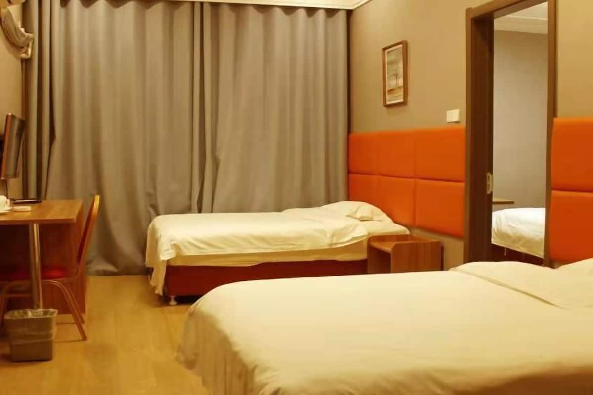 A hotel room with two beds, a desk, and a chair.