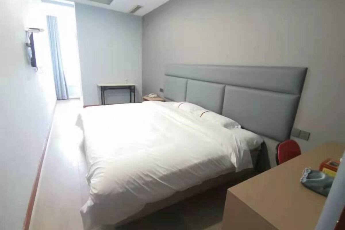 A hotel room with a large bed, a desk, and a chair.