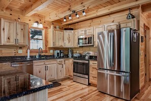 A modern kitchen with wooden cabinets, stainless steel appliances, and a granite countertop.