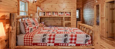 A log cabin bedroom with a bed, a bench, and a ceiling fan.