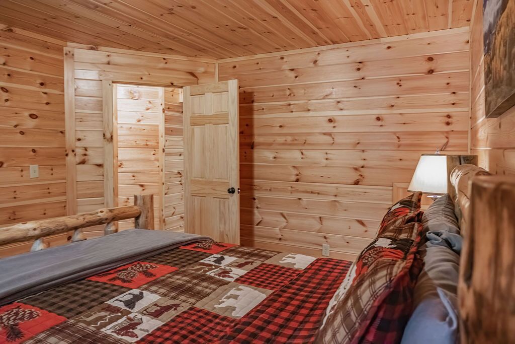 Ein Holzblockhaus-Innenraum mit einem Bett, einer Bank und einer Tür.