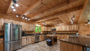 A spacious kitchen with wooden cabinets, stainless steel appliances, and a large island. - Blue Ridge Lodge Hocking Hills: Accessible Luxury (Logan)