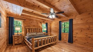A wooden cabin bedroom with a bed, nightstands, and a ceiling fan. - Blue Ridge Lodge Hocking Hills: Accessible Luxury (Logan)