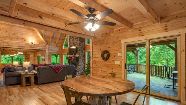 A wooden cabin interior with a dining table, chairs, a sofa, and a fireplace. - Blue Ridge Lodge Hocking Hills: Accessible Luxury (Logan)