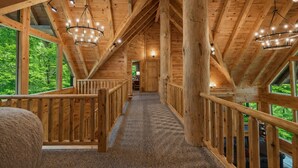 A wooden interior with a high ceiling, a central walkway, and large windows offering a view of greenery. - Blue Ridge Lodge Hocking Hills: Accessible Luxury (Logan)