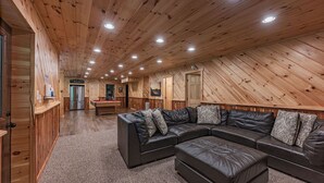 A spacious room with a large sectional sofa, wooden walls, and a ceiling with recessed lighting. - Blue Ridge Lodge Hocking Hills: Accessible Luxury (Logan)