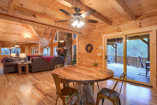 Cozy cabin interior with a dining table, sofa, and stone fireplace, perfect for relaxing in the forest.
