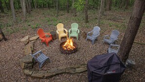 Un feu de camp entouré de fauteuils Adirondack, le tout situé dans un cadre forestier.