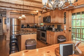 A kitchen with wooden cabinets, stainless steel appliances, and a granite countertop. - Black Bear Hideaway: Luxury Lodge in Hocking Hills (Rockbridge)