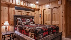 Una habitación con paneles de madera, una cama, una mesita de noche y un ventilador de techo.