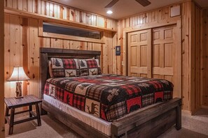 A wooden-paneled room with a bed, a nightstand, and a ceiling fan. - Black Bear Hideaway: Luxury Lodge in Hocking Hills (Rockbridge)