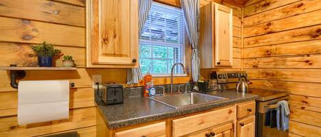 A wooden cabin interior with a kitchen featuring a granite countertop, stainless steel sink, and wooden cabinets.