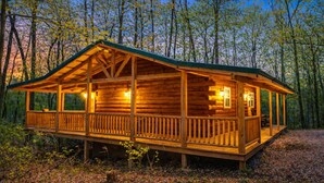 Eine Holzhütte mit Veranda, umgeben von Bäumen.