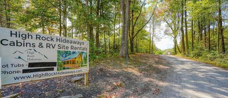 Une enseigne indiquant les locations de chalets et d’emplacements pour camping-cars de High Rock Hideaways, avec un paysage boisé en arrière-plan.