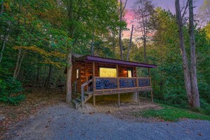 A wooden cabin with a balcony, surrounded by trees.